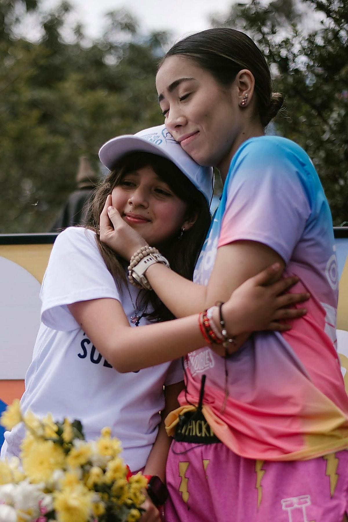 María hugging a girl from the foundation, eyes closed